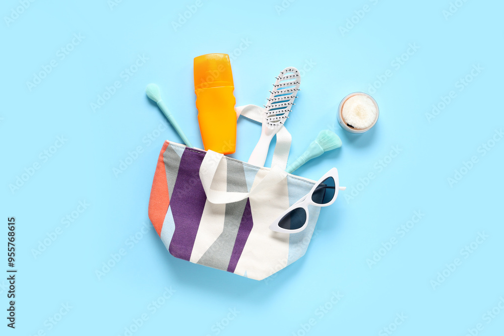 Wall mural cosmetic bag, sunscreen, comb, powder and sunglasses on blue background