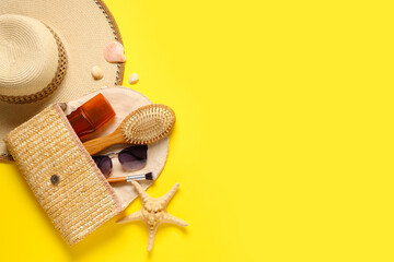 Beautiful composition with cosmetic bag, hat, accessories and sunscreen on yellow background