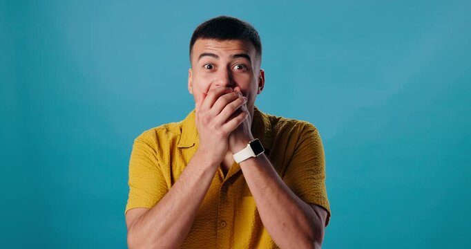 Surprise, wow or man in studio with face or hands on mouth for fake news, announcement or gossip. Blue background, shocked or portrait of person with crazy wtf expression for omg reaction or discount