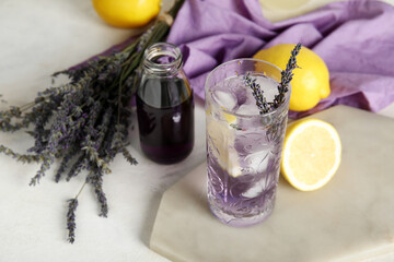 Glass of cold lavender lemonade, syrup and flowers on light table