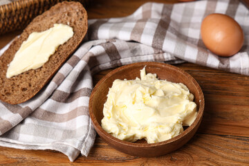 Plate with fresh butter, bread and napkin on wooden table
