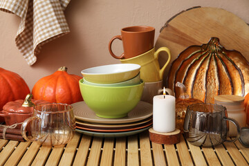 Different dishes, pumpkins and autumn decor on wooden table in kitchen