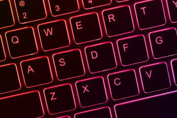 Close-up view of a backlit keyboard with keys glowing in shades of red and purple. It could be relevant for topics related to technology, typing or computer hardware.