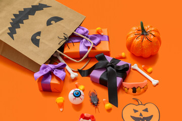 Composition with shopping bag, gifts and decorations for Halloween on orange background