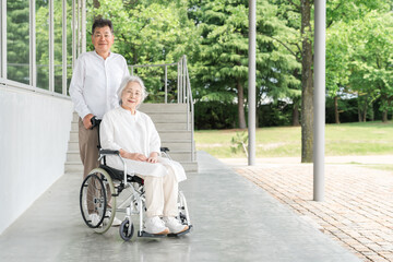 車椅子のシニア女性と介護するシニア男性（介護施設・老人ホーム・デイサービス・福祉のイメージ）
