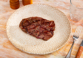 Appetizing roast piece of veal meat dished up in a plate on the laid restaurant table