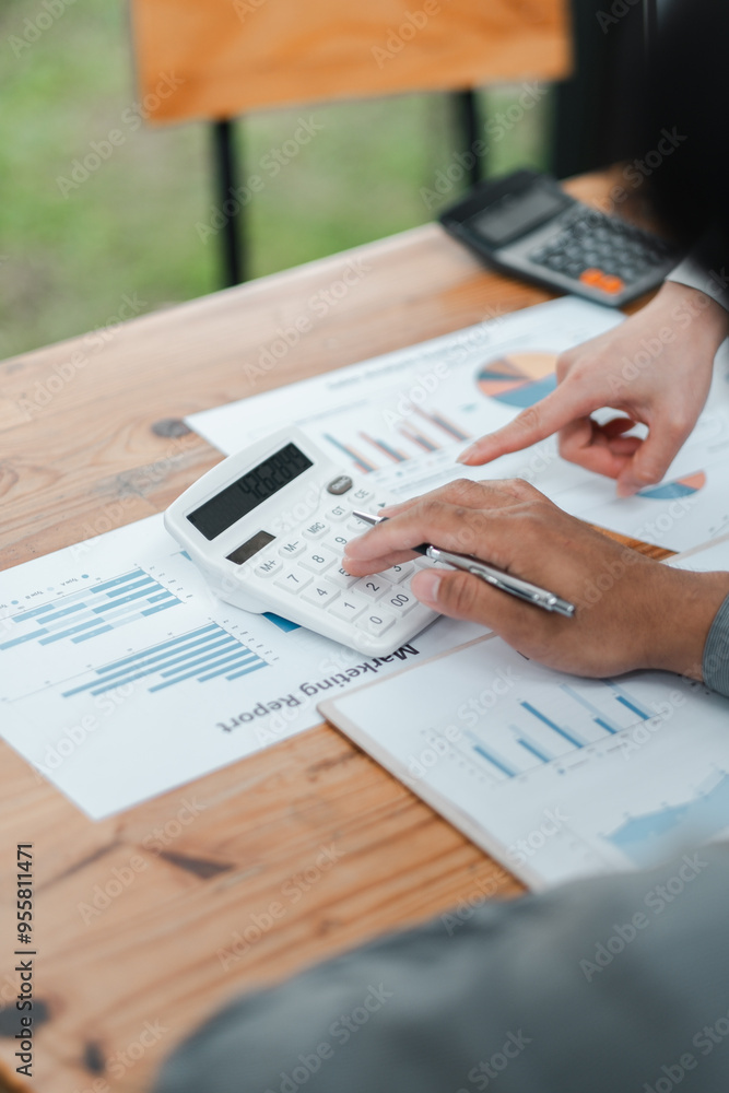 Poster close-up of hands using a calculator and analyzing financial reports during a business meeting on a 