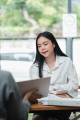 A young woman in a white shirt attentively listens during a business meeting in a modern office environment.