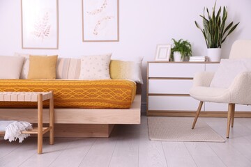 Large bed near white wall in room. Stylish bedroom interior