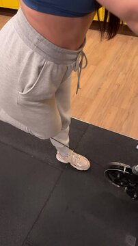 A woman exercising her hamstring muscle with a cable machine at the gym, working out her legs