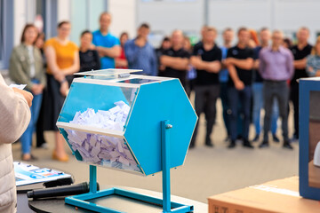 A blue box with a white paper inside is being held by a person, lottery or prize draw