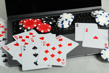 Online poker. Playing cards, chips and laptop on light grey table