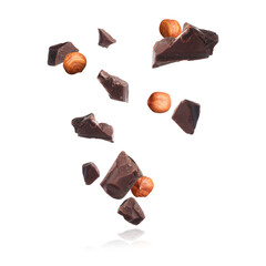 Pieces of tasty chocolate and hazelnuts falling on white background