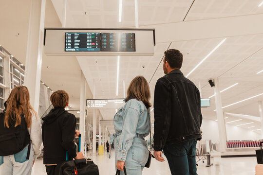 Family of 4 checking flight times on board at airport