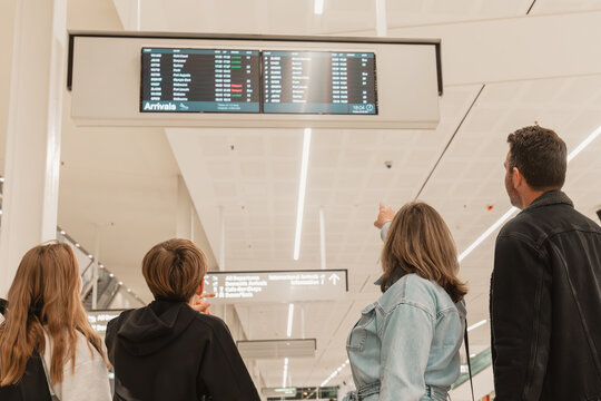 Family of 4 checking flight times on board at airport