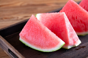 The cut watermelon in the wooden tray is very fresh