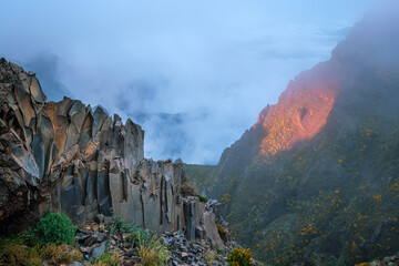 Mountains on sunset covered in fog and clouds with blooming Cytisus shrubs. Near Pico de Arieiro ,...