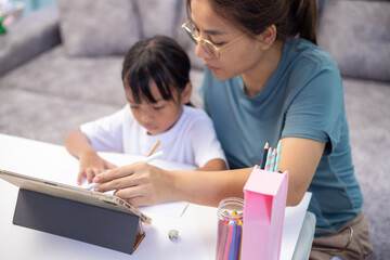 A woman and a child are sitting at a table with a tablet in front of them