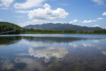 Summer view of Gwacheon Reservoir with cloud reflection on water at Seoul Grand Park against Gwanaksan Mountain in the background near Gwacheon-si, South Korea