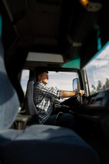 Vertical image, truck driver in the cabin on bright sunny day, looking ahead 
