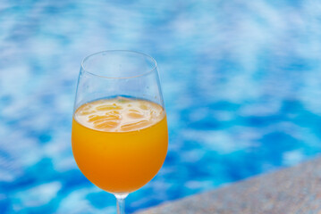 Orange juice cool drinks sweet freshness drinking poolside at blue swimming pool in tourist resort. Orange smoothie juicy healthy mocktail organic cool juice glass. Sweet healthy beverage cool drinks