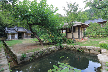 Gangjin-gun, Jeollanam-do, South Korea - August 2, 2021: Summer view of a pond and the main gate of roof titled house with thatched house at Baekdongwon Forest