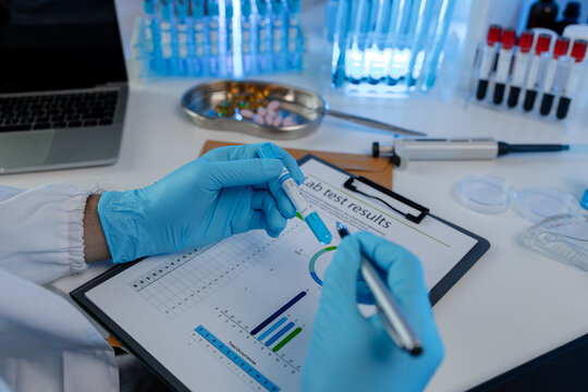 A scientist is reviewing lab results and documents receives from researchers involved in chemical testing, chemist is concentrating on reading test results document