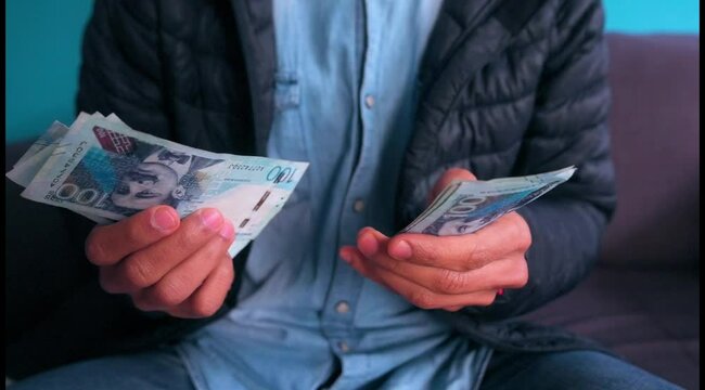 Man counts Peruvian 100 soles bills.