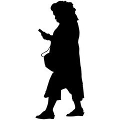 A woman walking while looking at her phone in silhouette