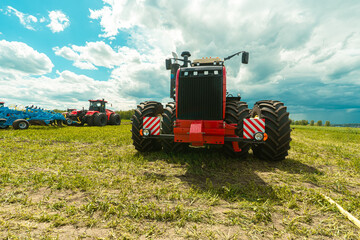 Red tractor working in a field on a bright sunny day. The concept of work in a fields and...