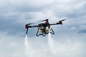 Modern technologies in agriculture. industrial drone flies over a green field and sprays useful...