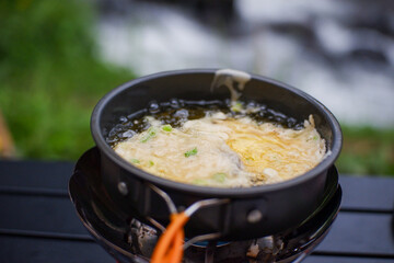 gas burner for frying food in outdoor camping. Cooking outside with blur river background