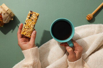 Granola bar with cup of tea in female hands