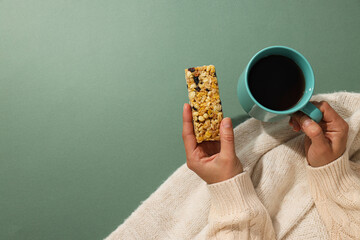 Granola bar with cup of tea in female hands