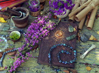 Mystic still life with magic book of spells, paper scrolls and witchy ritual objects on old table....