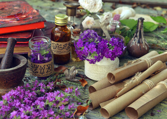 Mystic still life with magic book of spells, old paper scrolls and witchy ritual objects on old...