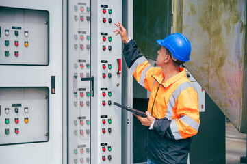 The electrician inspects a large-scale industrial electrical control system, focusing on the safety and stability of the electrical system.