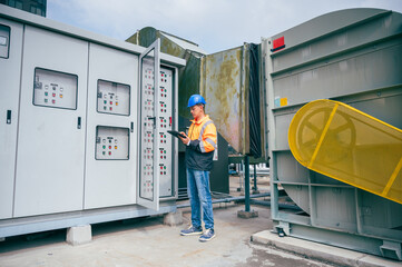 The electrician inspects a large-scale industrial electrical control system, focusing on the safety...