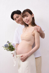 妊娠した若い妻と花束を持って寄り添う夫