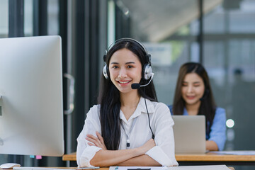 Young asian businesswoman with headset using desktop computer for customer support and online...