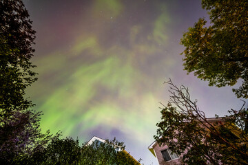 A mesmerizing display of the Aurora Borealis illuminates the night sky above a residential...