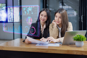 Two Asian young businesswomen using tablet with analyzing financial charts in the modern office, Business financial documents and planning idea project concept.