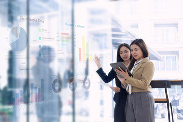 Two Asian young businesswomen with analyzing financial data charts and business presentation plan in the modern office, Business financial documents and planning idea project concept.