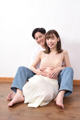妊娠した若妻と優しく寄り添う若い夫
