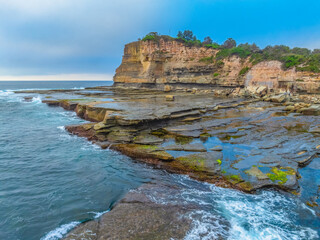 Sunrise seascape and rocky Inlet with thick fog cloud over the ocean at the Terrigal Skillion on the Central Coast of NSW, Australia.