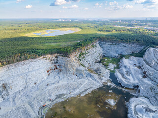 Naklejka premium Stone quarry in the forest. Flying over the summer mixed forest during sunset. The surroundings of Yekaterinburg. Ural, Russia, Aerial View