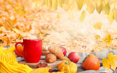 Autumn picnic in the park. Cup of coffee, apple and croissants on picnic blanket on nature yellow leaves. Active lifestyle concept