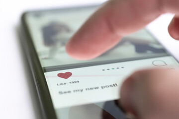 A follower puts a like under the post of a favorite blogger. Girl using mobile smart phone