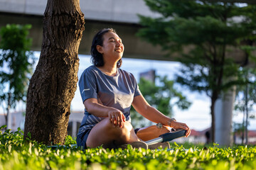 Woman with prosthetic leg from amputation is relaxingly practicing meditation yoga in the park to...