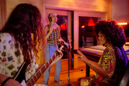 Portrait of a hispanic woman producer working with a band in a music studio